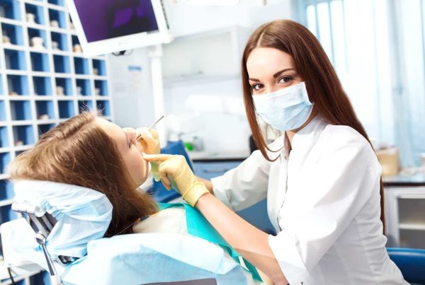 Klinikai fogászati higiénikus képzés visszanézhető órákkal és online jegyzetekkel a Pannon Kincstár iskolában. Barna hajú fogorvos kezeli a páciensét.