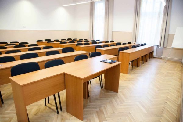 Iskolaterem a Pannon kincstár felsőoktatás intézményében. Fekete székek és összetolt iskolapadok várják a tanulókat. Terembérlés.