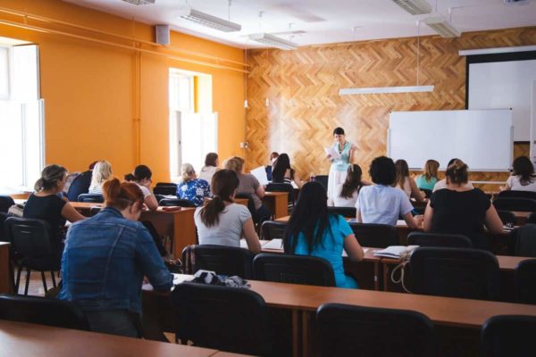 Oktatás a Pannon Kincstár tantermeiben. Tanárnő, ahogy az órán a szorgalmas tanulóknak magyarázza a képzés anyagát. A Tanulás egy megújult, modern szintje. Terembérlés.