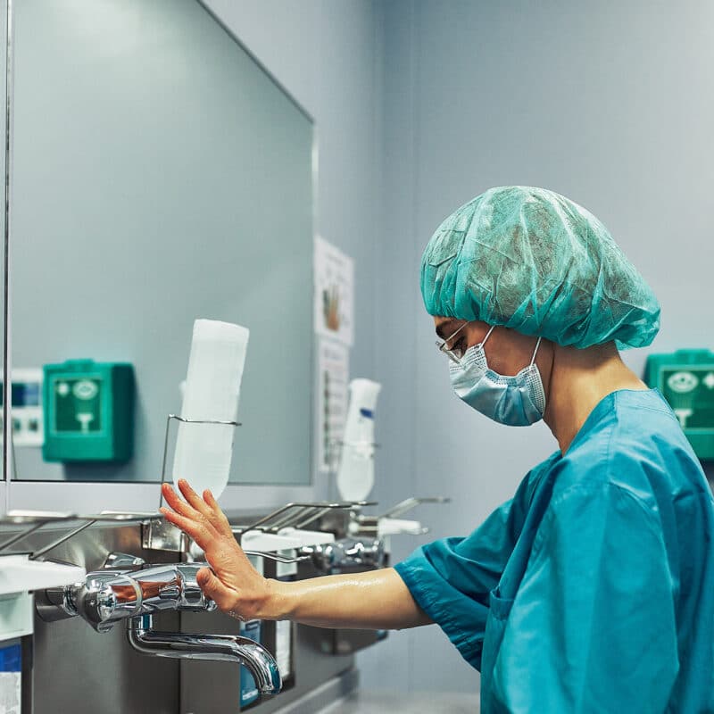 Fiatal nő egészségügyi védőfelszerelésben, maszkban sterilizáló műszerekkel sterilizál. Fertőtlenítő-sterilező képzés, Pannon KIncstár szakmai cikk